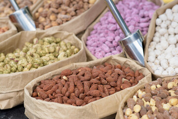 Almonds and pistachios with spices lie in paper bags on the counter.