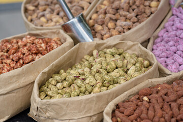 Almonds and pistachios with spices lie in paper bags on the counter.