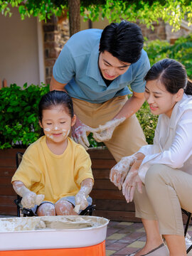 Happy family of three doing pottery together outdoors