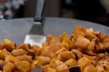 Chunks of fried potatoes in a large skillet during the street food festival.