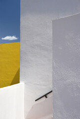 Minimalist surreal architectural composition with white and yellow walls on the blue sky and a lonely cloud background, Spain, Andalusia, bright sunlight