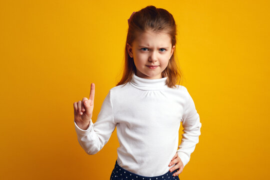 Displeased young girl waving index finger in no and prohibition gesture