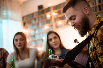 A group of friends on a house party playing guitar and drinking beer
