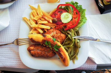 Fish espada with fried banana, french potatoes, kidney beans and fresh vegetables.