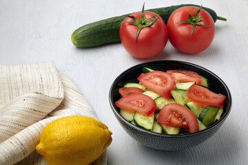 Bowl with chopped tomatoes and cucumbers seasoned with lemon