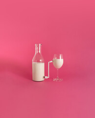 Bottle with beverage connected with a charger to a full glass , on pink background.