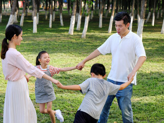 Happy family of four playing in the park