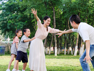 Happy family of four playing in the park