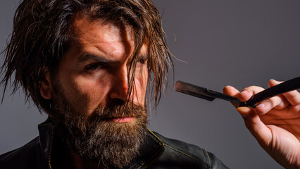 Professional beard care. Handsome bearded man with barber razor. Barbershop.