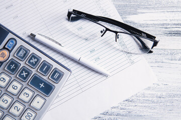 paper, calculator and glasses on the table. desktop concept