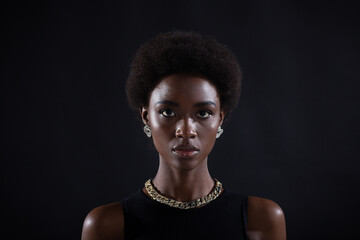Close up full face portrait of serious african american woman with afro hairstyle on black studio background.