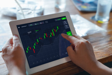 Investor using digital tablet check investing account dashboard and analyze stocks price on online marketplace for buying investment. Online stock trading. Forex