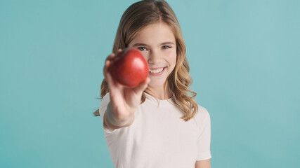 Portrait of pretty teenager girl offering red apple and smiling