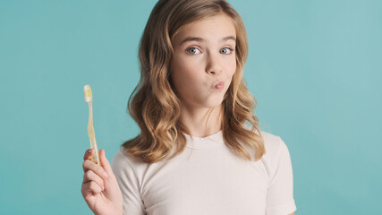 Portrait of attractive teenage girl posing with toothbrush over