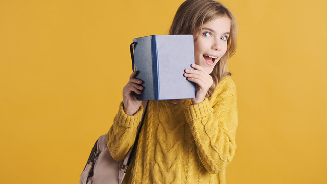 Positive teenager student girl dressed in sweater peeping from b