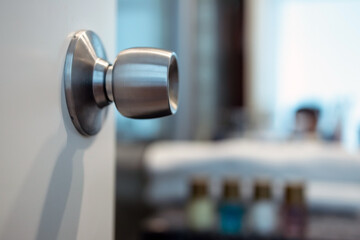 round steel stainless door handle-lock on the open white door to the bathroom. Copy space - 438894199