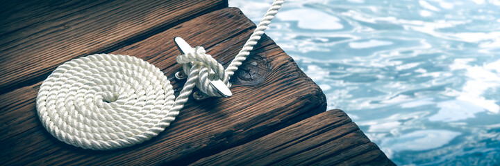 Coiled Boat Rope Secured To Cleat On Wooden Dock  - obrazy, fototapety, plakaty