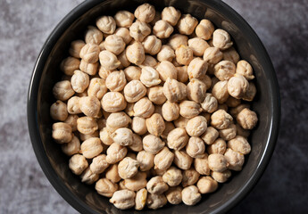 Chickpeas in a bowl against a stone background.