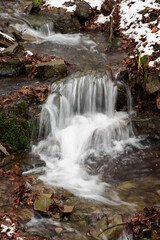 Fototapeta na wymiar Water flowing in the river between the stones in winter.