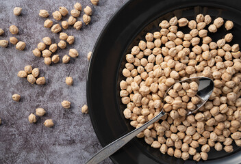 Chickpeas in a black dish against a stone background.