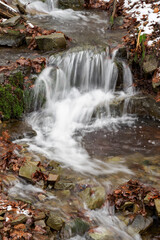Fototapeta na wymiar Water flowing in the river between the stones in winter.