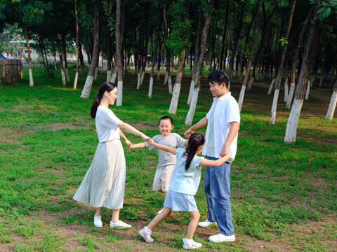Happy family of four playing in the park