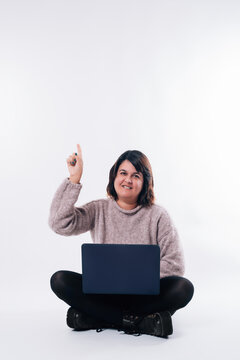 Vertical image of sitting woman with laptop pointing up. Copy space