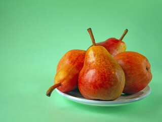 red pears on the white plate with green background