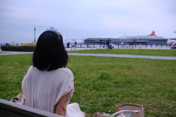 座って港を見る女性