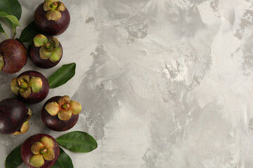 Fresh ripe mangosteen fruits on light grey table, flat lay. Space for text