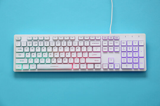 Modern RGB keyboard on turquoise background, top view