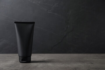 Tube of men's facial cream on grey stone table. Mockup for design