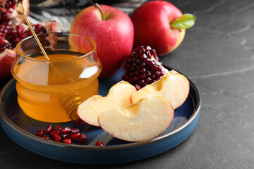 Honey, pomegranate and apples on black table, closeup. Rosh Hashana holiday