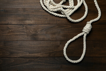 Rope noose on wooden table, top view. Space for text