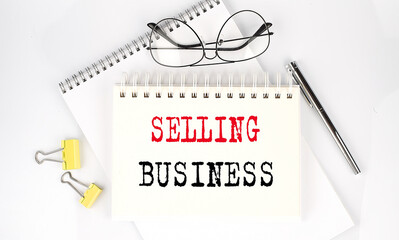 SELLING BUSINESS text on the notebook with pen,clips and glasses