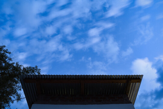 Long exposure of roof sheets from below and running clouds above rooftop