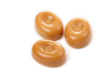 Three caramel candies on a white background close-up.