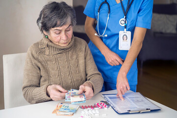 An elderly gray-haired woman with glasses reads a health insurance contract and signs it. The...