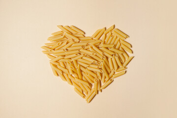 Food background and valentine concept. Pasta in shape of heart on light pink background.