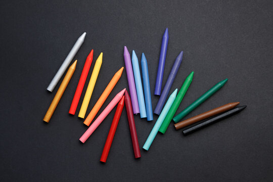 A set of colorful crayons in the form of a rainbow on the table. Children's school pencils on a dark background.