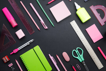 Stationary concept, Flat top view Photo of school supplies scissors, pencils, paper clips, sticky note, stapler and notepad in pink tones on a dark background with space to copy, flat view.