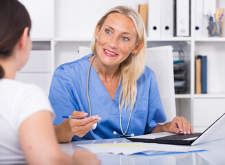 Female doctor working with patient in medical office and writing prescription