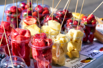 Street vendor of various fruits cut into transparent plastic cups
