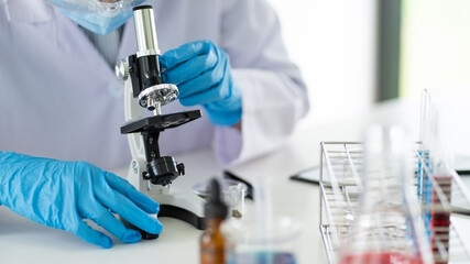 Young Asian scientist Working looking through a microscope doing research for analyzing a...
