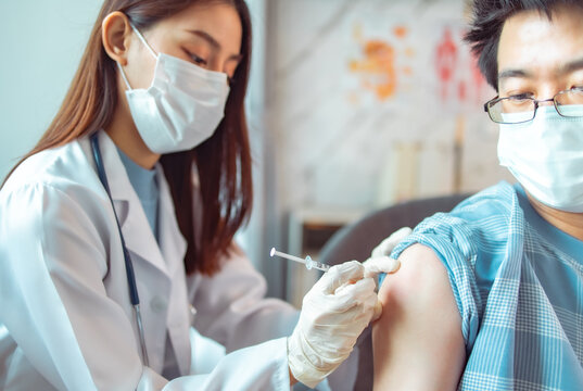 Vaccination, immunization, disease prevention concept. people in medical face mask getting Covid-19 or flu vaccine at the hospital. Professional nurse or doctor giving antiviral injection to patient.