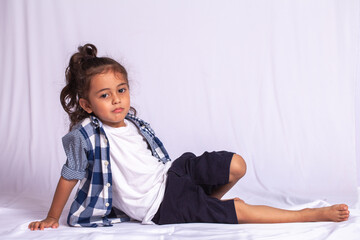 Naklejka premium Handsome stylish little boy wearing a plaid shirt over a white t-shirt stands and poses in a white scene..white background.studi shot.The concept of independent play of the child..