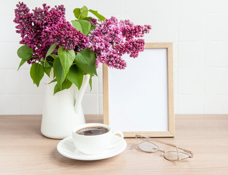 Bouquet of lilac flowers in a vase and empty wooden frame