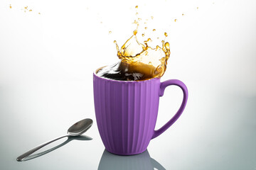 splash from a lump of sugar in a purple mug on a white background