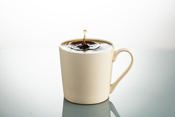 splash from a lump of sugar in a cream colored mug on a white background