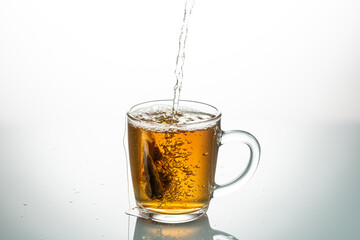 making tea from a tea bag in a transparent mug on a white background
